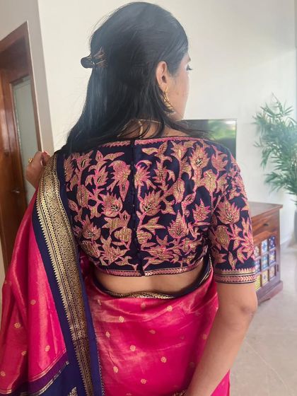 The graceful Neha in a bespoke hand-embroidered blouse. The navy blue blouse with pink and gold floral embroidery is paired with a pink saree.