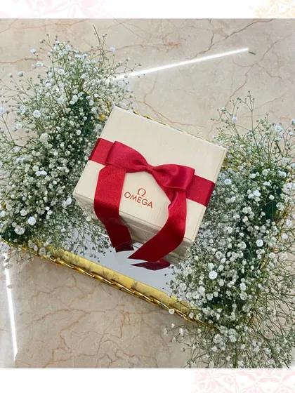 A timeless gift presented beautifully. This Omega watch box is nestled in a bed of baby's breath on a mirror tray, creating a simple yet incredibly luxurious trousseau piece.