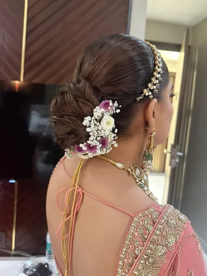 A closer look at a textured bridal bun for a D-day look. I've woven in fresh baby's breath and purple flowers to match the bride's pastel lehenga, creating a soft and romantic feel.