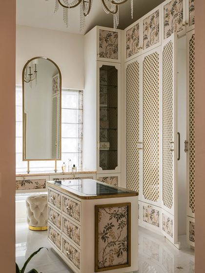 The bespoke walk-in closet at Verdant Manor, featuring floor-to-ceiling wardrobes with classic latticework and floral panel inlays. The central island provides storage and a surface for accessories.