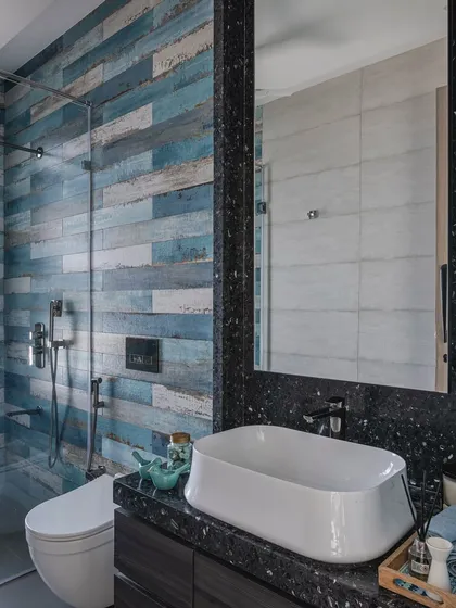 We used tiles with a distressed blue wood finish to give this bathroom a rustic, coastal feel. The dark terrazzo countertop and simple white basin balance the look, creating a space that is both unique and calming.