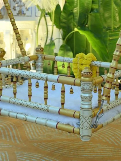 A close up of the beautifully crafted cradle, or palna, for a naming ceremony. I decorated it with delicate yellow flowers and ensured the bedding was soft and comfortable for the baby.