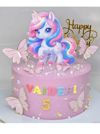 A cute and colorful unicorn cake for a 5th birthday. This fresh pineapple cake features a bright unicorn topper, rainbow lettering, and pink butterflies.