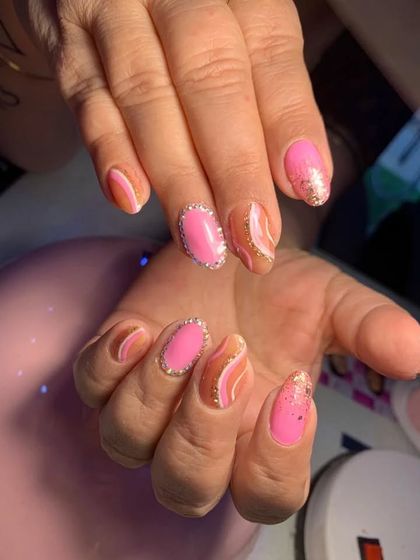 A pretty pink design with abstract swirls, gold glitter, and a delicate crystal outline on the accent nails.