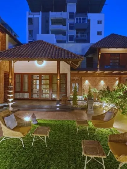 At night, the 'Anandi' house comes alive with warm lighting that highlights the texture of the exposed brick and the traditional sloping roofs.