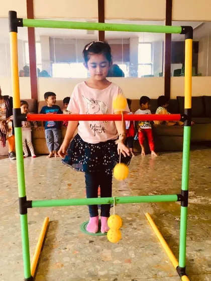 A young girl carefully aims her shot in the ladder toss game. I ensure every child gets a chance to practice and develop their skills at their own comfort level.