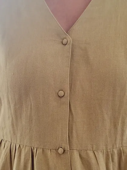 A close-up on the button details of the olive green dress.
