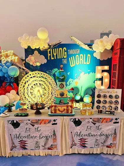 The full dessert table, including the main cake, a donut bar, cakesicles, and tarts, all following the travel theme.