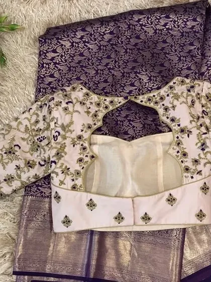 This blush pink blouse features a unique back design with a keyhole opening at the top and a bustier-style lower half, all adorned with floral embroidery.