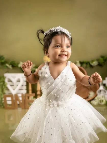 A princess in white. This little girl is a vision of joy in her beautiful dress and tiara for her first birthday portraits.
