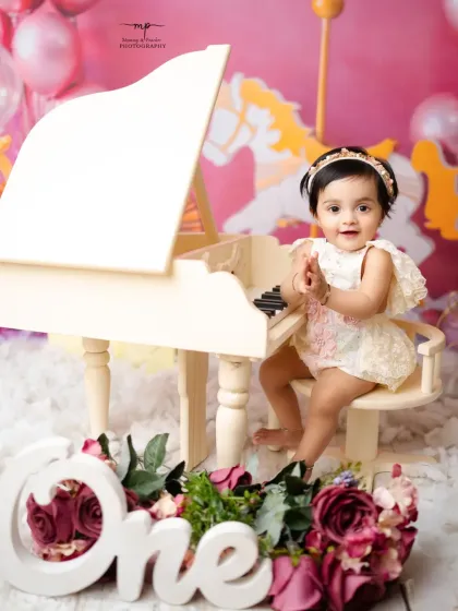 A beautiful portrait of a one-year-old at her piano, surrounded by flowers. The soft pink theme creates a dreamy and celebratory atmosphere.