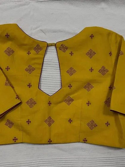 I design ready-to-wear pieces that blend traditional craft with modern style. This mustard yellow cotton blouse features classic Kasuti embroidery motifs and a contemporary keyhole back, making it a versatile and elegant addition to any wardrobe.