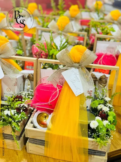 A close-up of our festive hampers assembled in rustic wooden crates. These gifts are bursting with color, featuring fresh flowers, bright yellow tulle wrapping, and a mix of delightful products, ideal for vibrant celebrations.