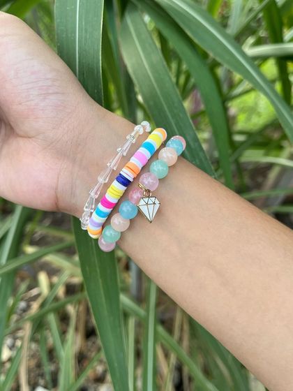 A vibrant and playful bracelet stack with colorful clay beads and a sparkly diamond charm. This is a fun accessory that can be added to any hamper to make it extra special.