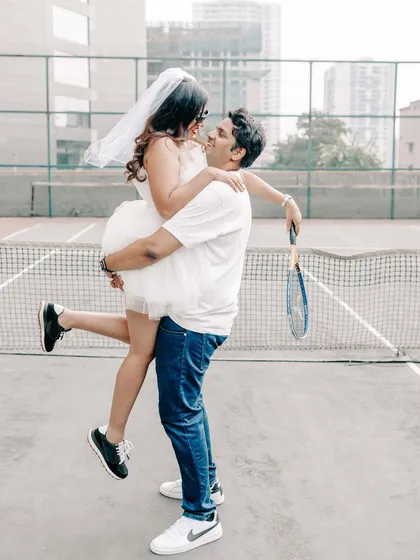 A fun and loving lift on the tennis court. This shot is all about celebrating the couple's playful dynamic in a unique and modern pre-wedding setting.