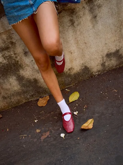 A playful shot of our red studded ballet flats paired with white socks and a denim skirt. This styling shows the versatility of the shoe, easily dressed up or down for a more casual, youthful vibe.
