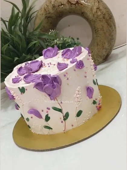 There is something so beautiful about hand-piped florals. This cake features delicate purple flowers piped directly onto the buttercream, creating an artistic and textured design.