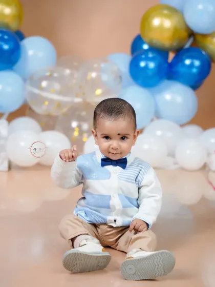 A sweet, simple portrait in a bow tie and sweater, capturing a gentle wave from the birthday boy.