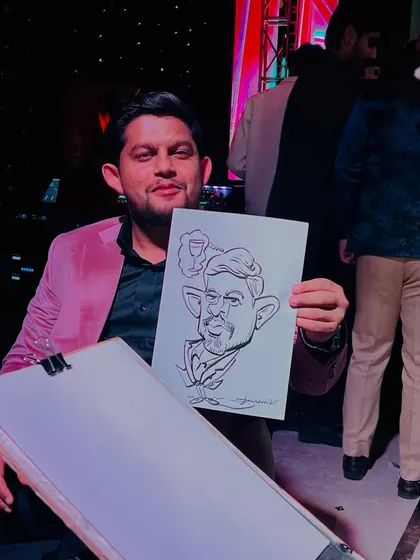 A guest in a stylish pink jacket holding his caricature, which includes a fun detail of a drink. It's all about personality.