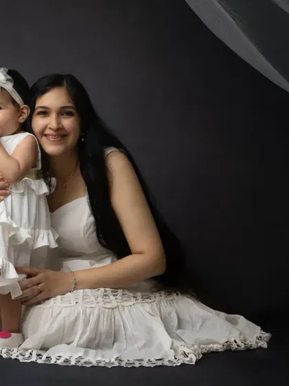 A mother and daughter moment in matching white dresses. The flowing veil adds a touch of softness and magic to this dark studio portrait.