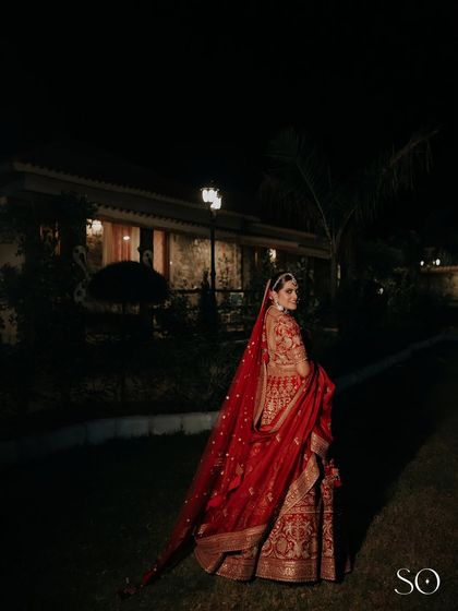 A beautiful shot of the bride in her deep red lehenga, exuding timeless elegance under the evening lights.