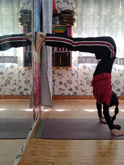 This is an advanced arm balance, a variation of Handstand (Adho Mukha Vrksasana) using the wall for support. This pose builds incredible upper body strength, focus, and confidence.