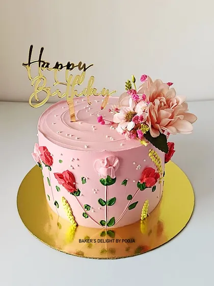 A pretty pink floral cake with hand-piped stems and leaves, topped with a delicate flower arrangement.