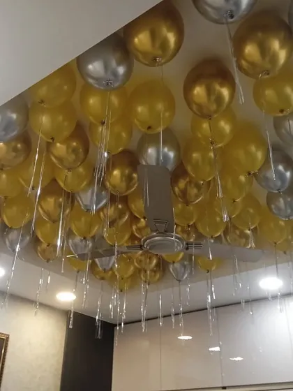 A ceiling full of metallic gold and silver balloons with dangling ribbons. This is a simple way to make a big impact and fill any room with a festive atmosphere.