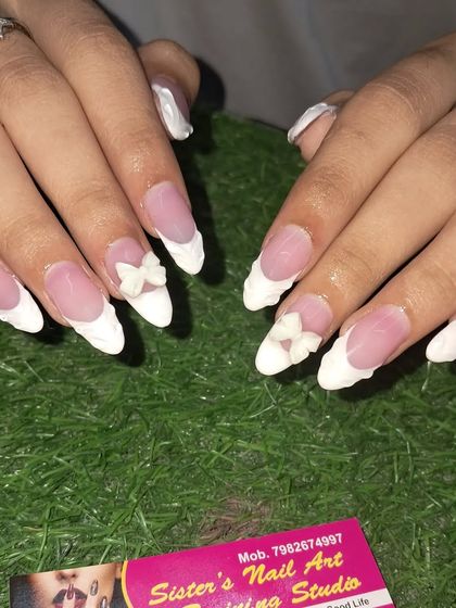 A delicate and feminine French manicure. These long almond nails feature sculpted white tips and a beautiful 3D bow on the accent nails for a soft, romantic feel.