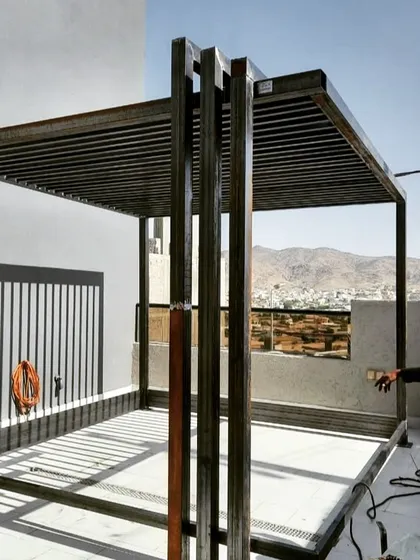 A behind-the-scenes look at the raw metal framework of a large pergola during construction. This shows the sturdy, welded-steel structure before the finishing materials are applied.