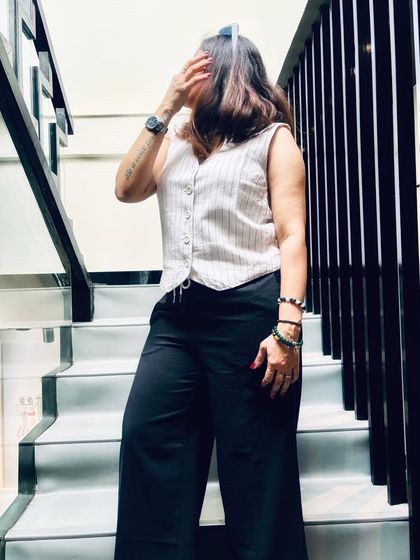 An artistic shot on a staircase. This outfit, with a pinstriped vest and black trousers, plays with classic tailoring to create a look that is both modern and timeless.
