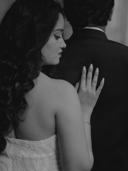 A delicate black and white close-up focusing on the bride's hand on her partner's back, highlighting intimacy and detail.