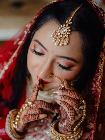 A close-up on the bride's face, her delicate nath and the soft glam makeup are the focus.