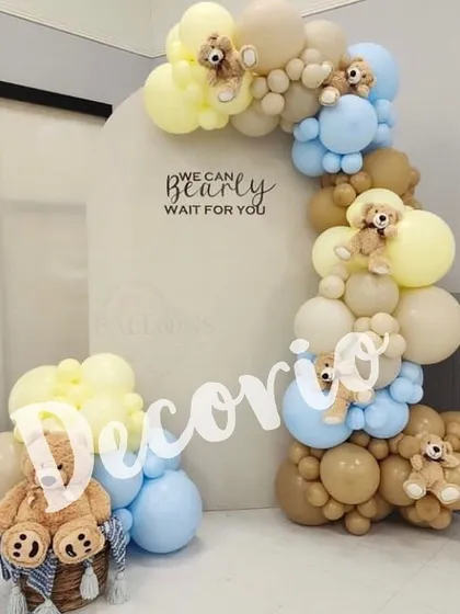 Here is another take on the "We Can Bearly Wait" theme, using a soft color palette of blue, yellow, and tan. The balloon arch is dotted with tiny teddy bears, adding an extra layer of detail and charm to the baby shower decor.
