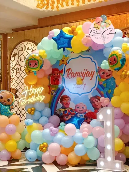 A vibrant and colorful Cocomelon themed party we organized. This setup features a custom character backdrop, a multi-colored balloon arch, and a light-up number '1' to celebrate a first birthday.
