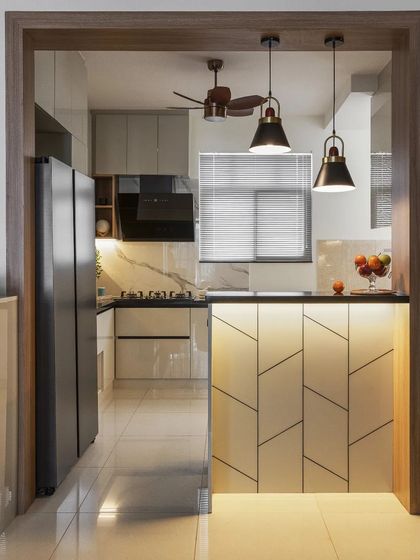 A stunning kitchen transformation featuring an open layout and a breakfast counter with a unique leaf-patterned front. The grey acrylic cabinets and black granite countertop create a modern and sleek aesthetic.