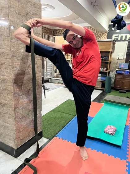 A male student demonstrates excellent flexibility in Trivikram Asana with the help of a belt. Our classes are for everyone, and props help each person practice at their own level.