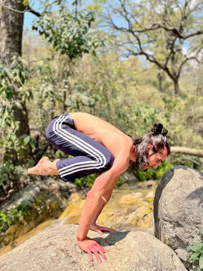 Bakasana (Crane Pose) on a rock in nature, showing strength and adaptability.