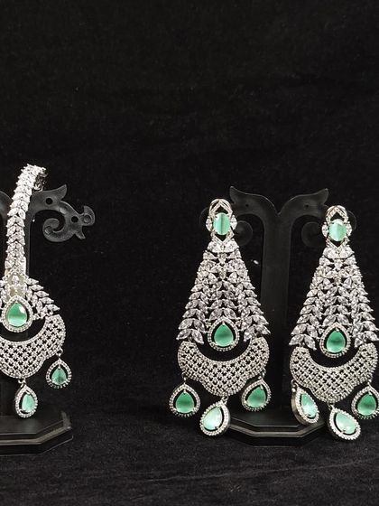 This image shows a full set of accessories available for rent: statement earrings and a matching maang tikka.
