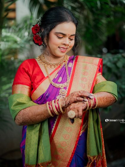 The bride looks down at her hands, adorned with intricate henna. This shot focuses on the traditional details and her serene expression during her engagement day.