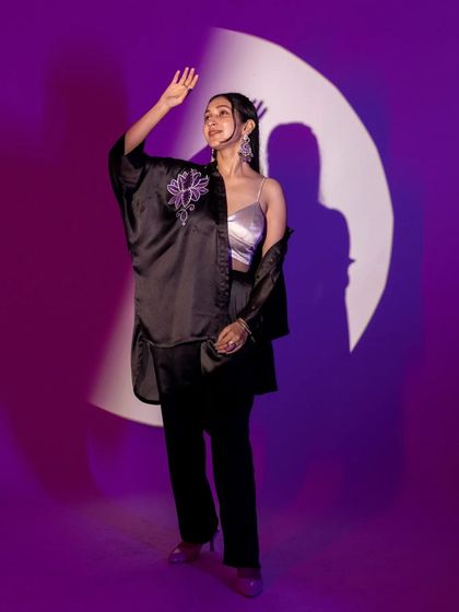 A full-length shot demonstrating the use of shadows and light play. The circular spotlight creates a frame within a frame, drawing the eye to the model and her stylish ensemble.