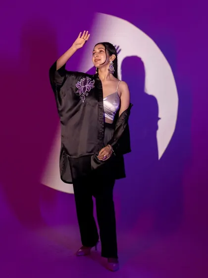 A full-length shot demonstrating the use of shadows and light play. The circular spotlight creates a frame within a frame, drawing the eye to the model and her stylish ensemble.