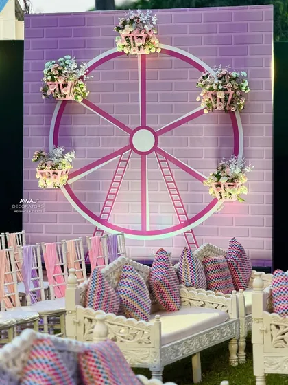A unique Ferris wheel-themed backdrop for a Haldi or Mehendi, adorned with baskets of flowers.