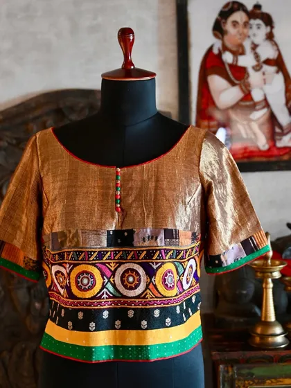 I design custom blouses that are as unique as the sarees they accompany. This kurti-style blouse is crafted from antique gold linen silk, detailed with a band of vibrant Kutch tribal embroidery and a patchwork trim made from studio scraps.