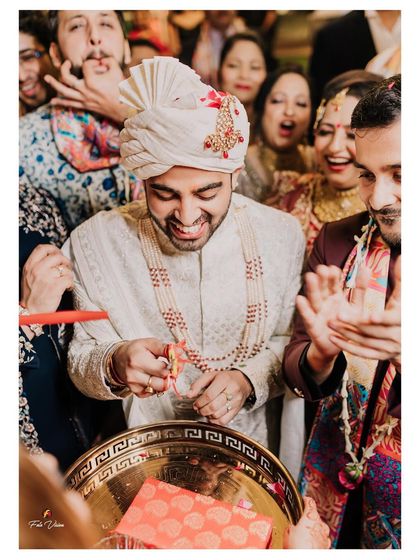 The groom's infectious smile during a wedding ritual, a candid moment of pure happiness surrounded by family.