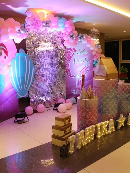 A magical mermaid-themed birthday decoration for Anvika. This setup includes a sparkling sequin wall, custom mermaid backdrops, themed cutouts, and a colorful balloon arch to create an underwater fantasy world.