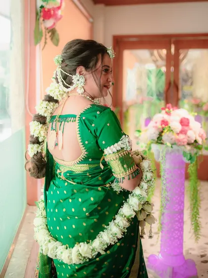 This view showcases the back of the floral jewellery set, including the intricate floral braid accessory (veni) and the elegant floral 'shela' draped over the shoulder.