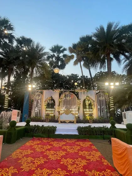 An elegant reception stage with fountains and topiaries. The design combines classic garden elements with a grand, ornate backdrop for a sophisticated evening affair.