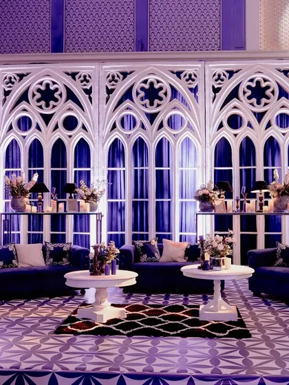 A lounge area set against a backdrop of large, white Gothic arch panels. The deep blue sofas and dramatic lighting created a sophisticated and moody corner for guests to relax.
