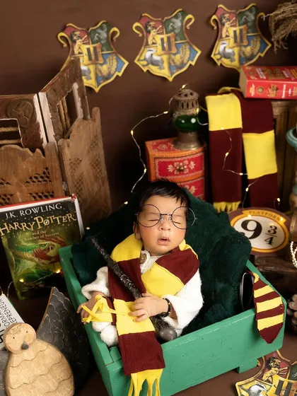 With his round glasses and Gryffindor scarf, this newborn is the spitting image of a tiny Harry Potter, ready for magical adventures at Hogwarts.